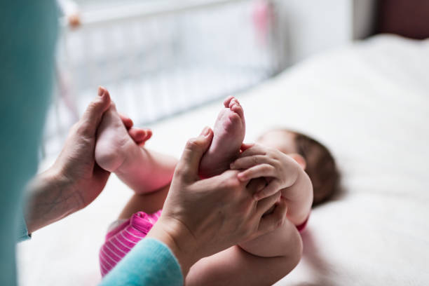 Petit bébé recevant un massage ostéopathique des pieds.